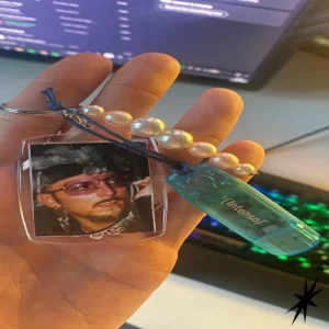 hand holding a transparent USB stick with the Intenso logo on it and a Gigi D'Agostino charm attached.